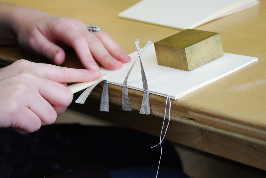 Artist sowing together signatures of a binding.