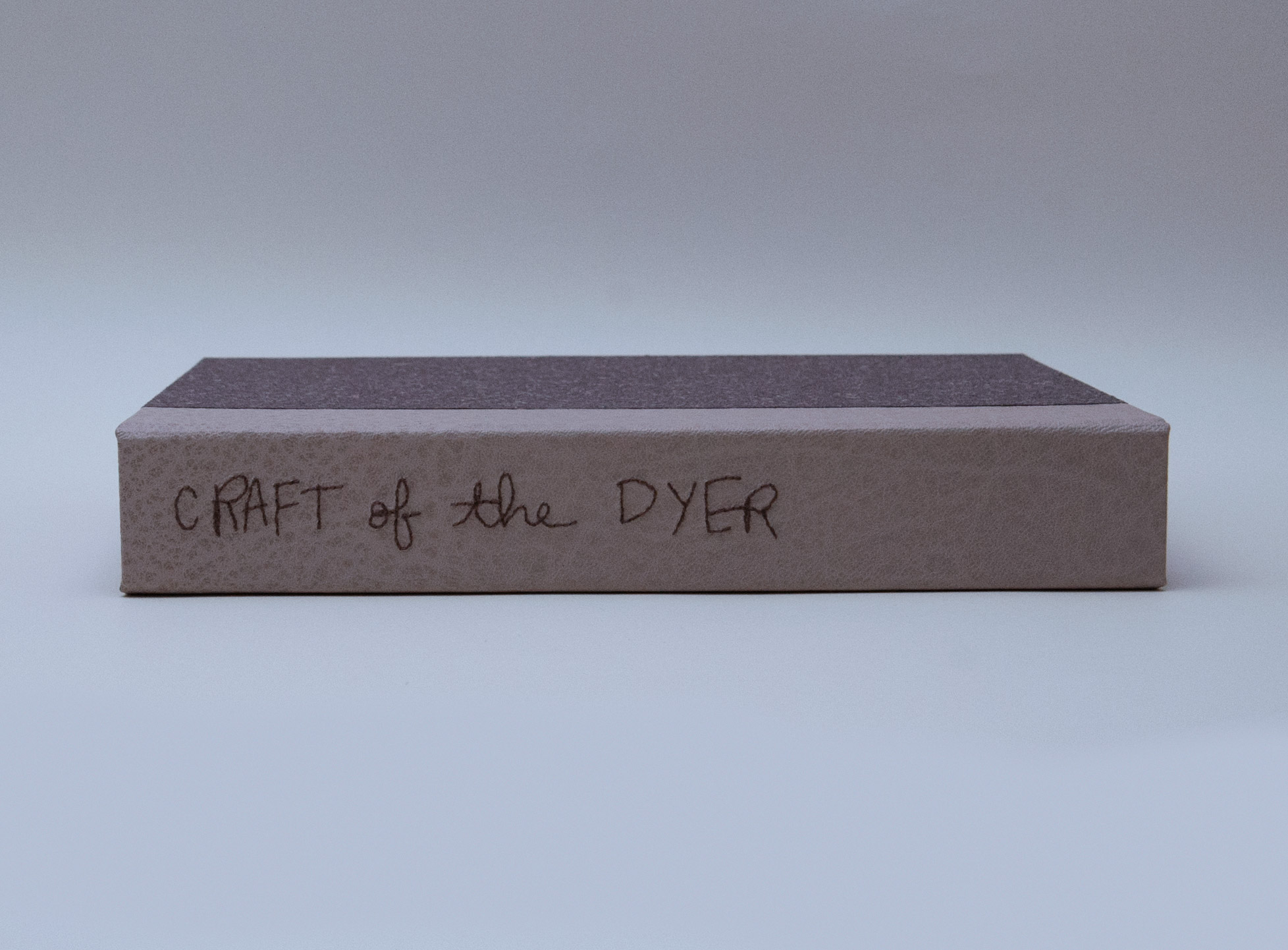 Box spine of Craft of the Dyer binding on a white table.