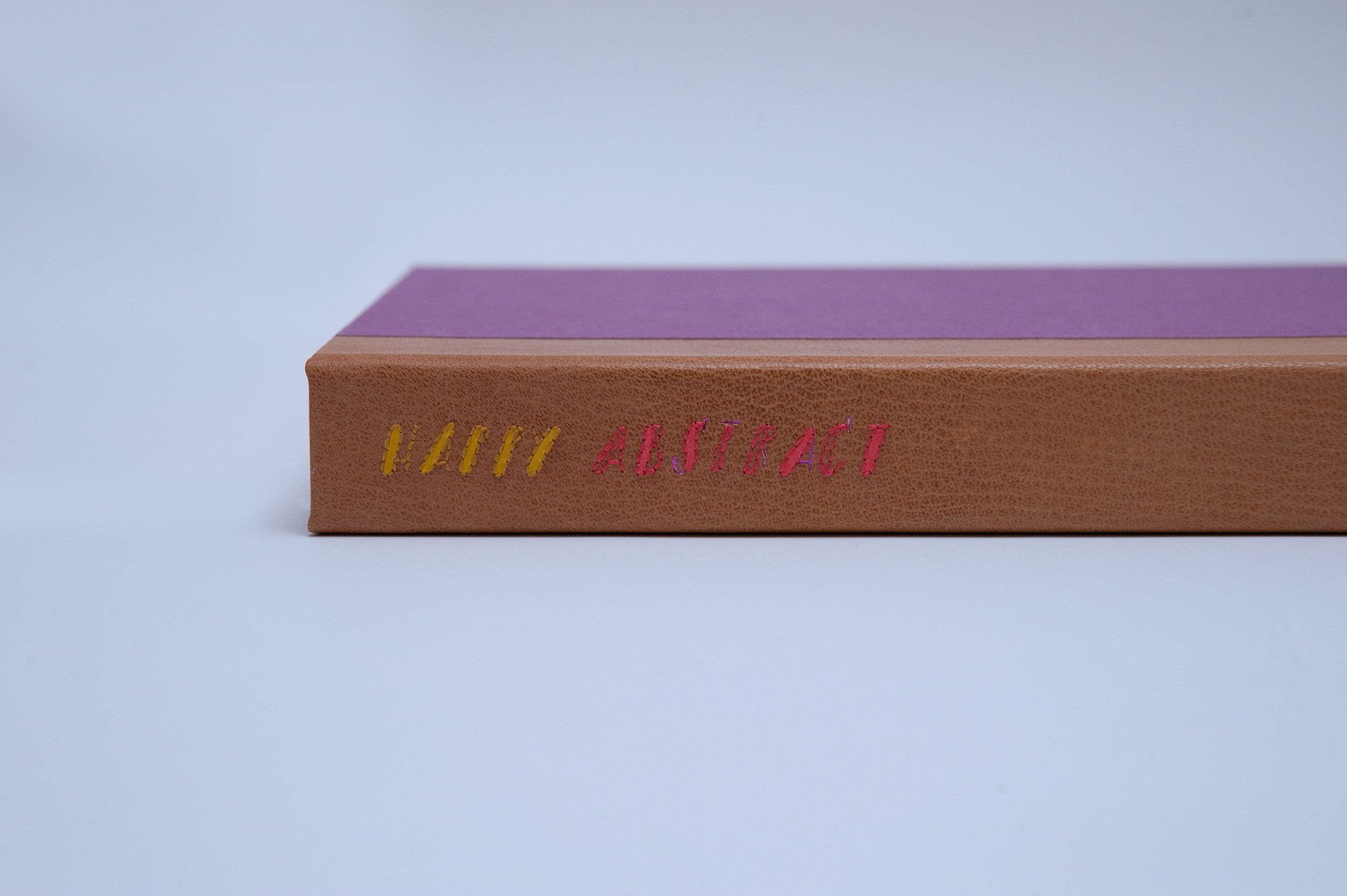 Box spine of Happy Abstract binding on a white table.