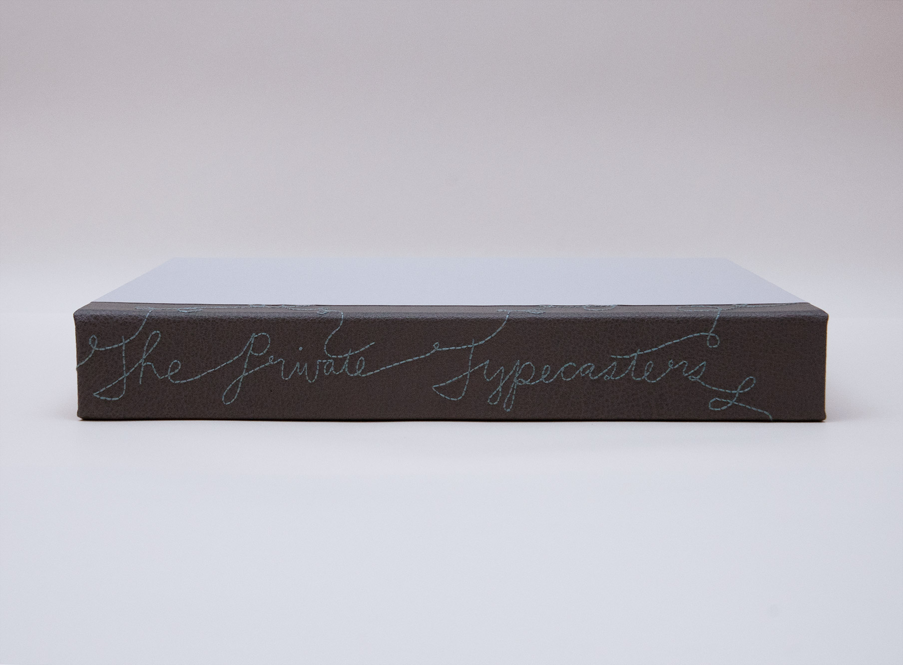 Box spine of The Private Typecasters binding on a white table.