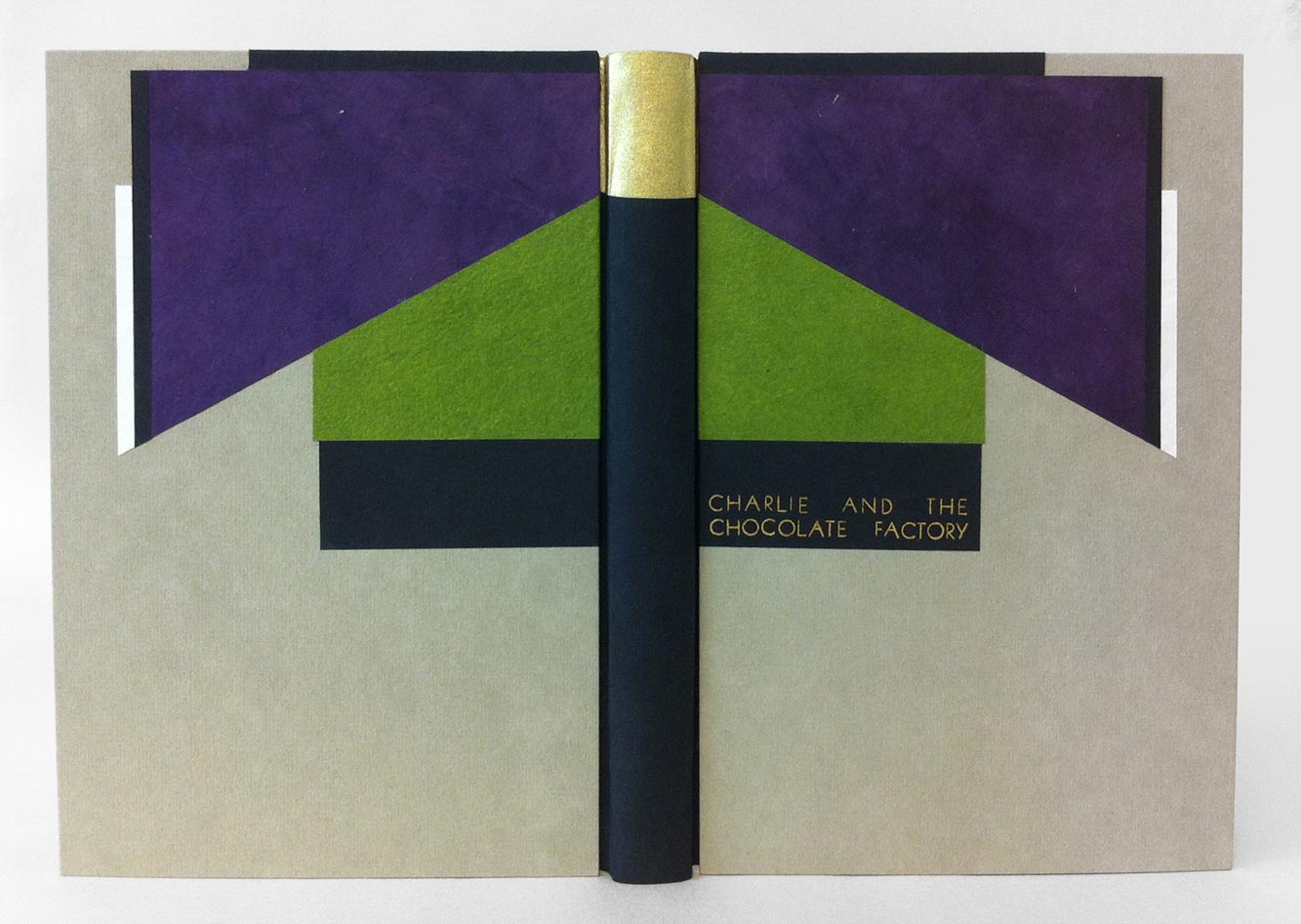 Front cover of Charlie and the Chocolate Factory binding on a white table.