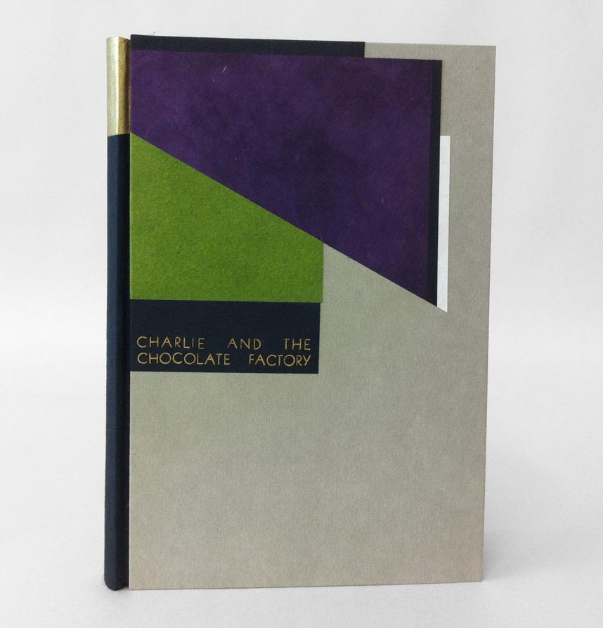 Front cover of Charlie and the Chocolate Factory binding on a white table.