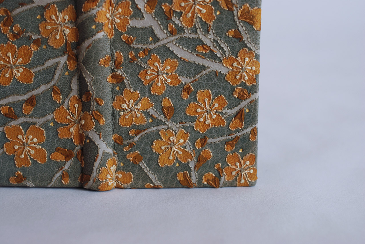 Close-up of front cover of The New House binding on a white table.