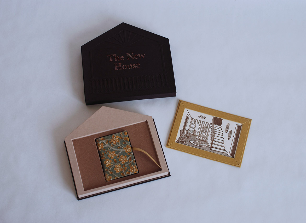 Box interior, print, and The New House binding on a white table.