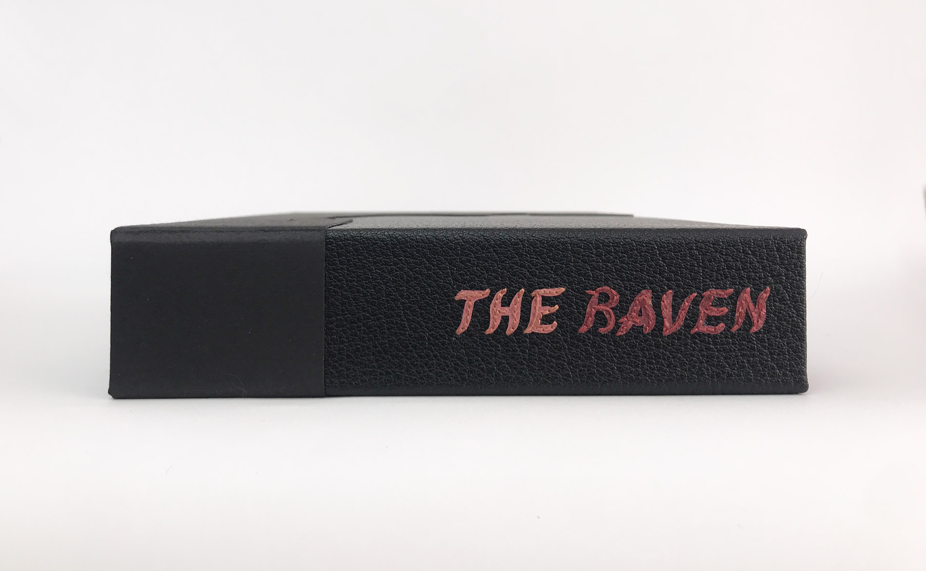 Box spine of The Raven binding on a white table.