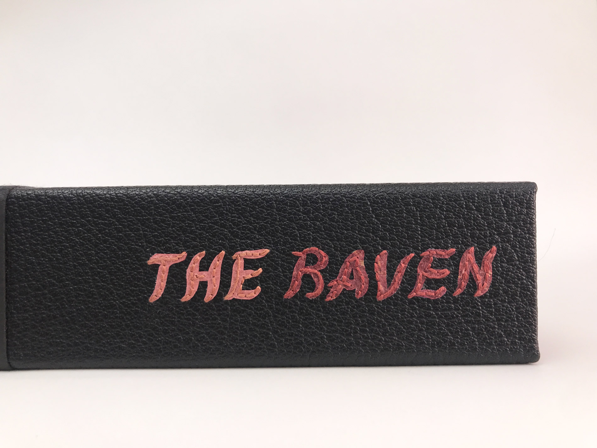 Close-up of box spine of The Raven binding on a white table.