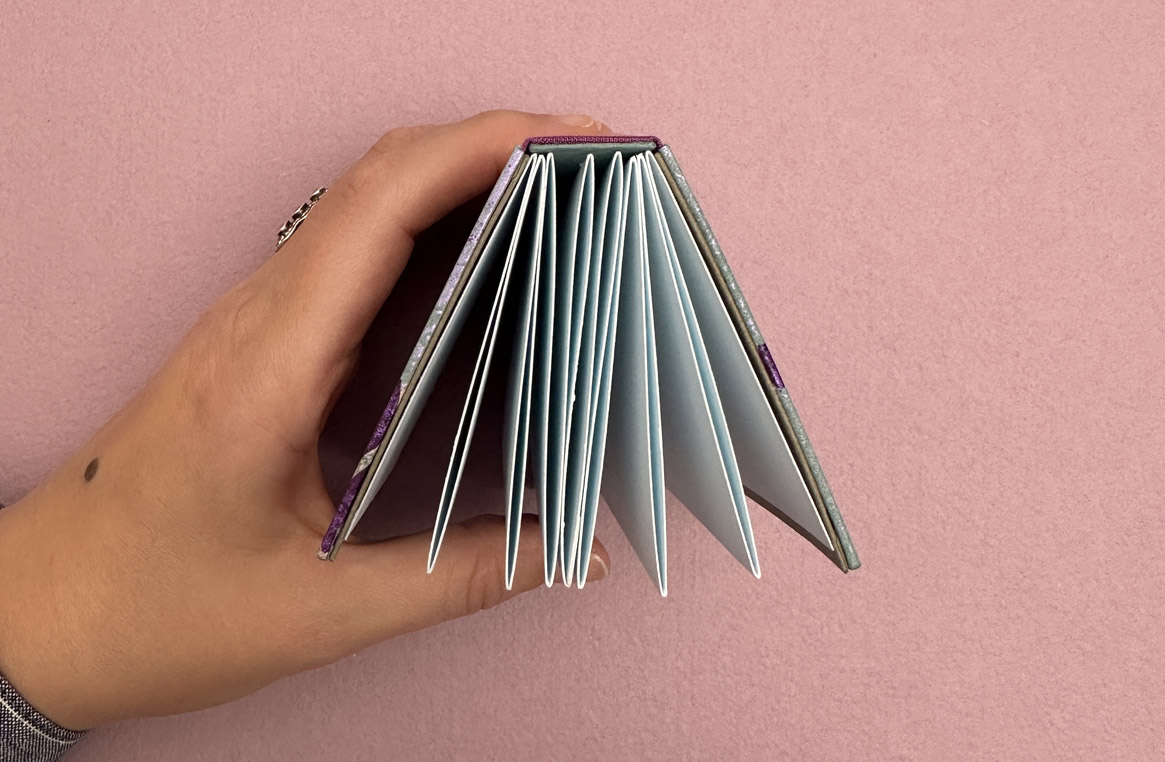 Two variations of the Dos-a-dos Binding standing upright on a wooden table.