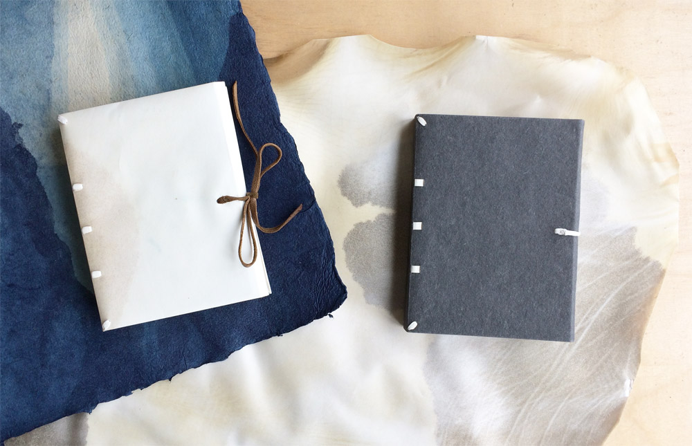 Limp Vellum Binding and paper case binding laying on a wooden table.