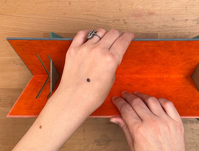 Opening up a punching cradle on a wooden table.