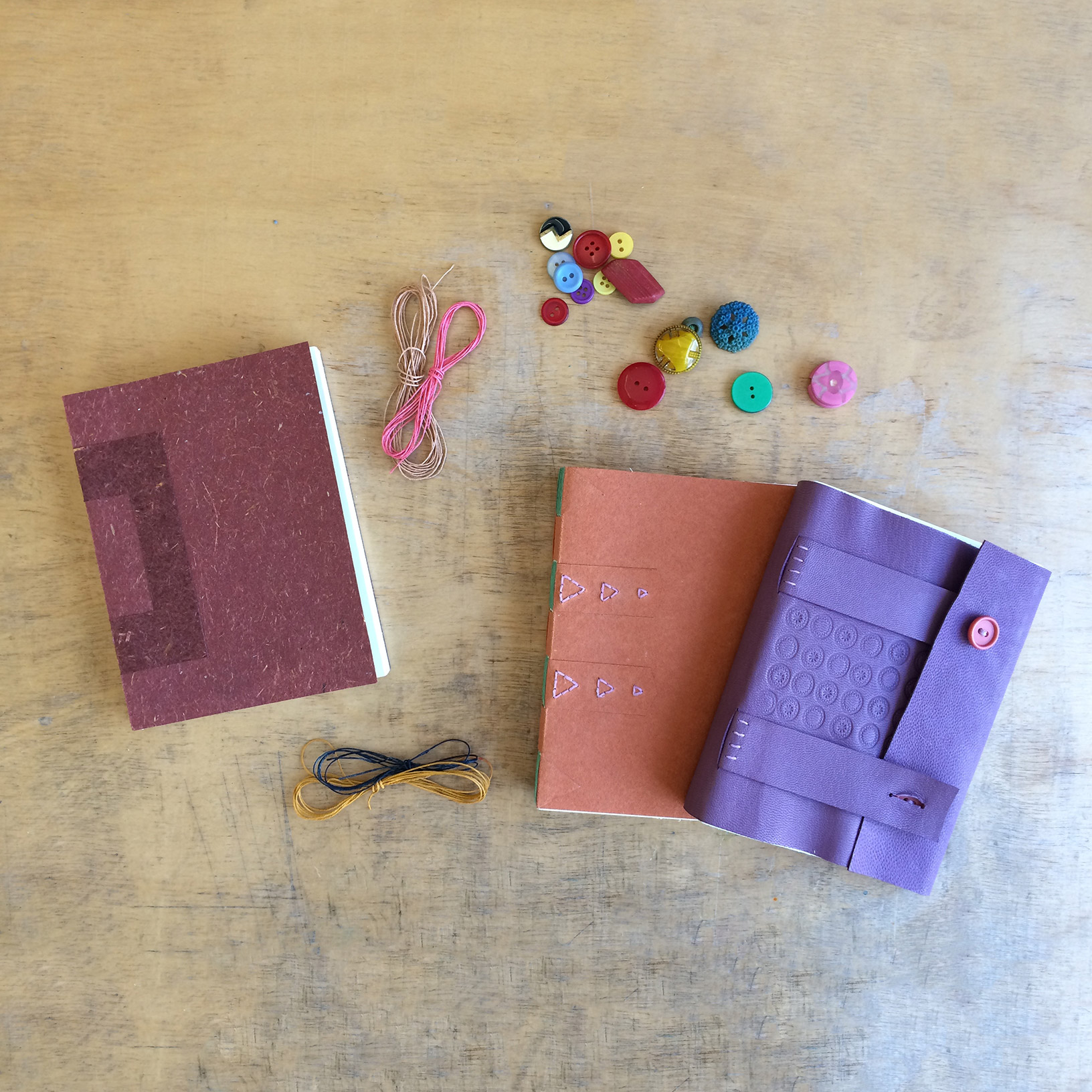 A variety of Cross Structure bindings sitting on a wooden table with some bookbinding materials.