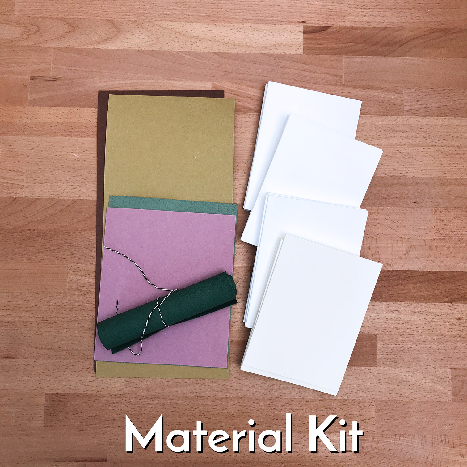 Bookbinding materials for the Cross Structure Binding workshop sitting on a wooden table.