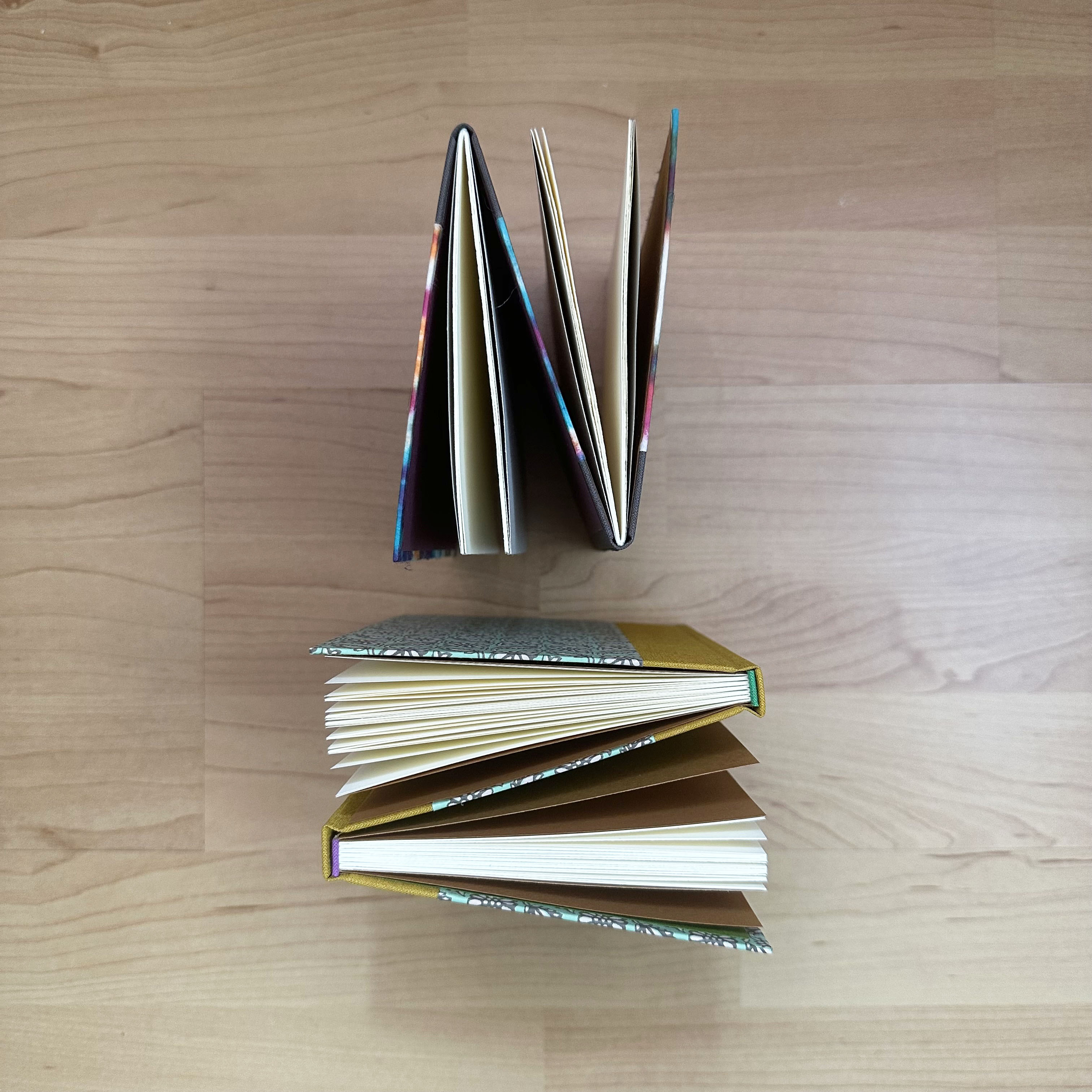 Top view of a variety of Dos-a-dos bindings on a wooden table.