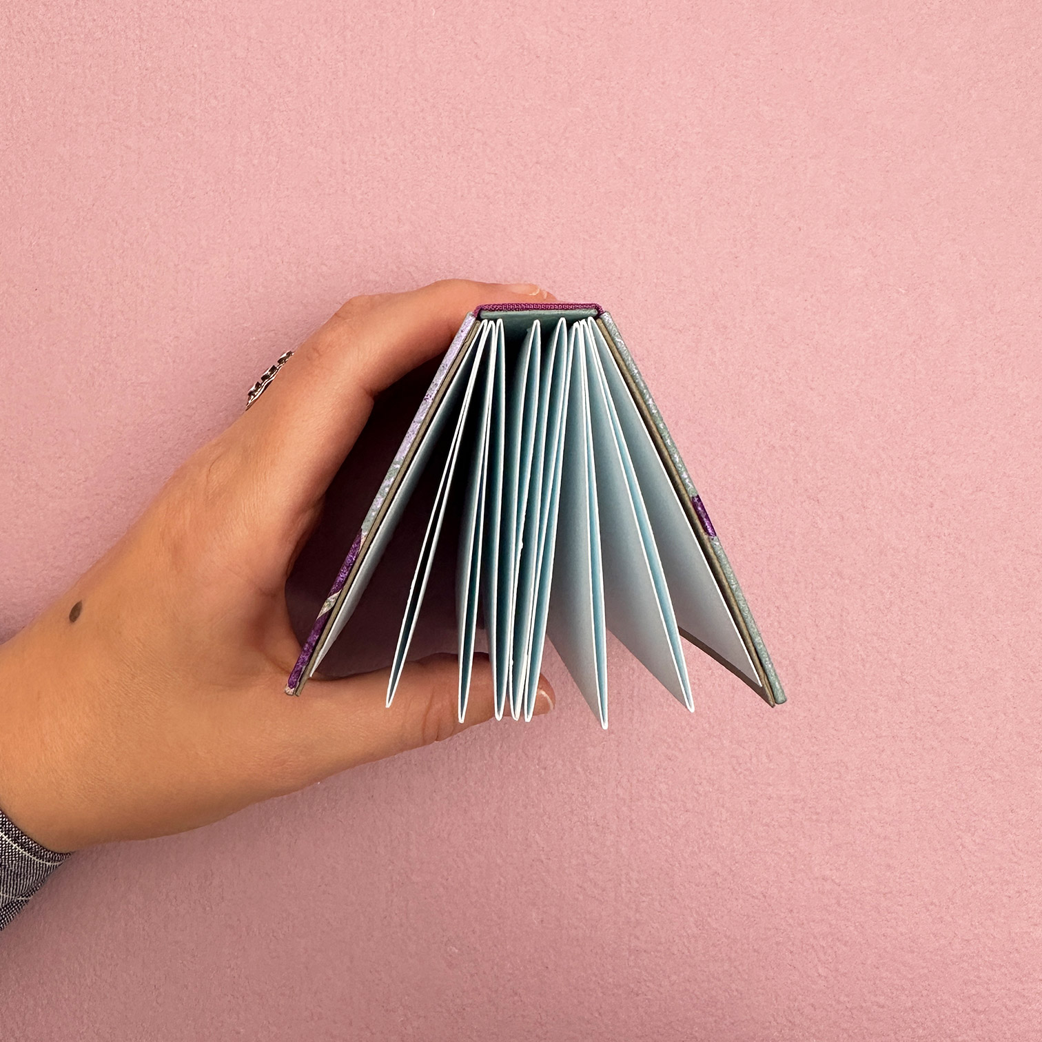 Head edge of the double panel binding with hand cupping left-hand side of book.