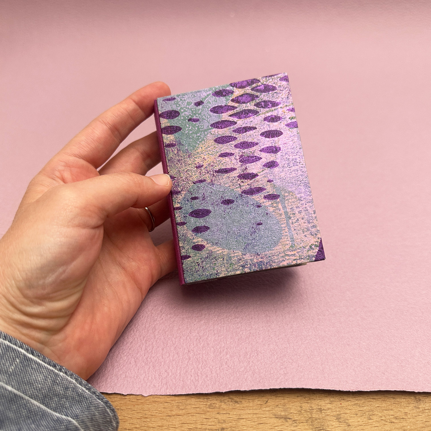 Showing the front cover of the double panel binding with lilac handmade paper backdrop.