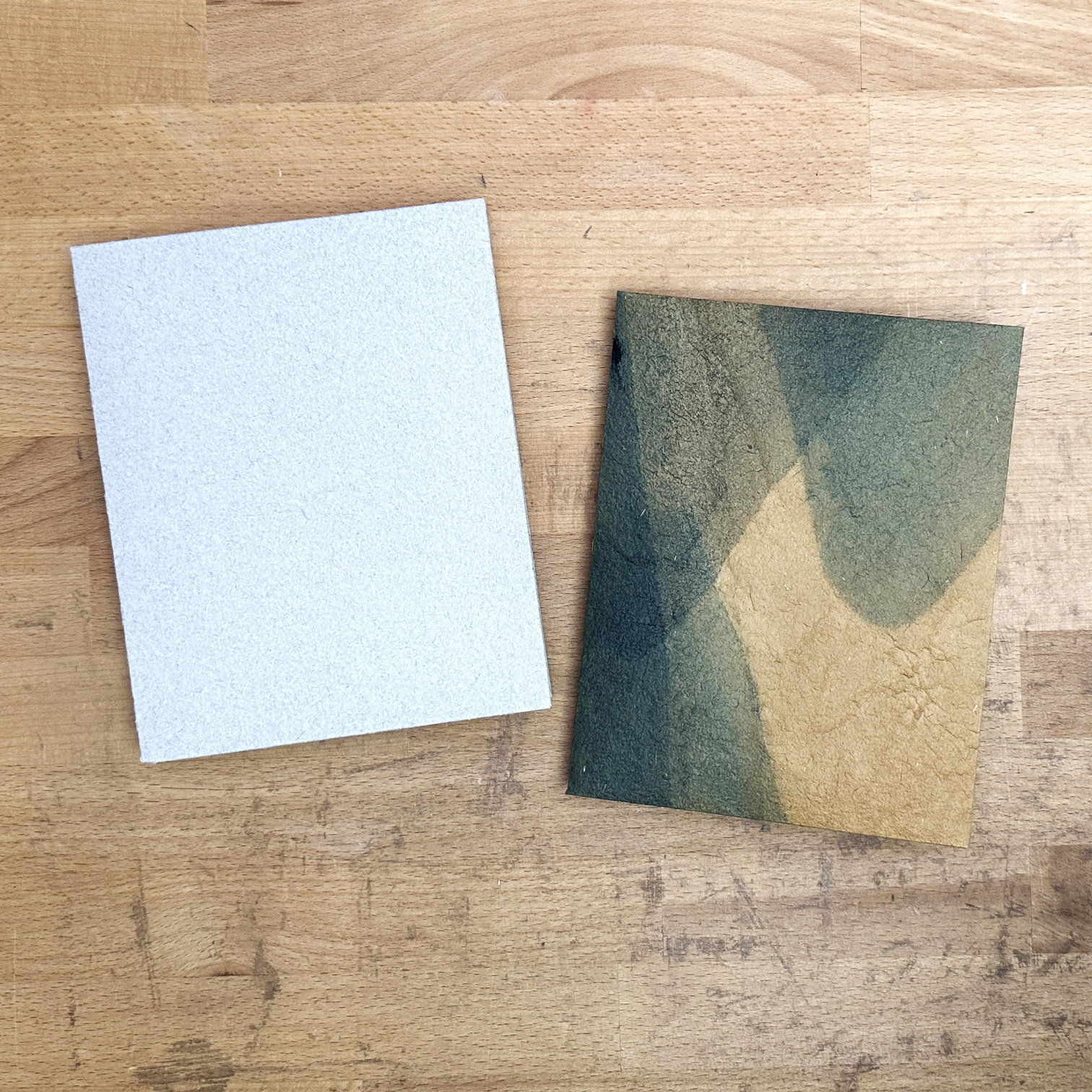 Two Envelope Bindings sitting on a wooden table.