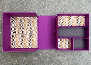 A clamshell box opened up sitting on a handmade paper.