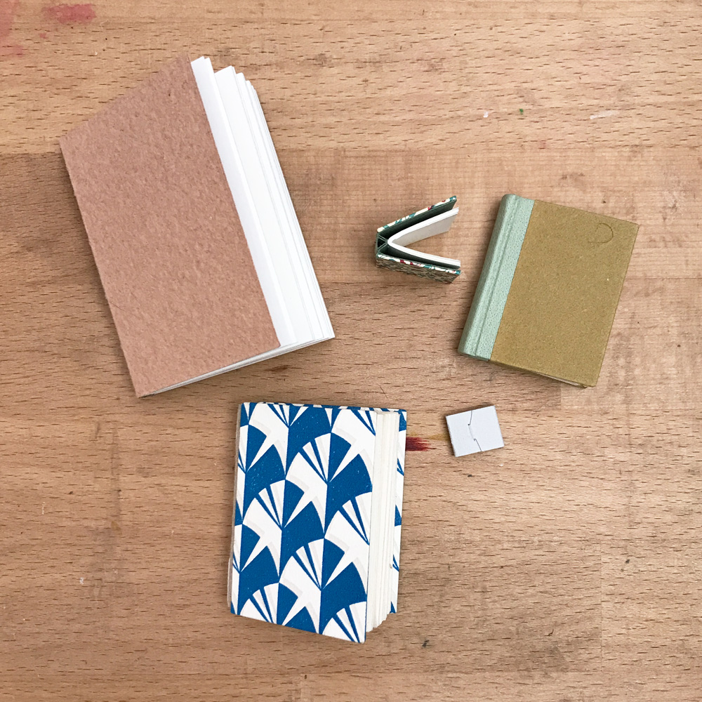 A variety of Miniature Bindings sitting on a wooden table.