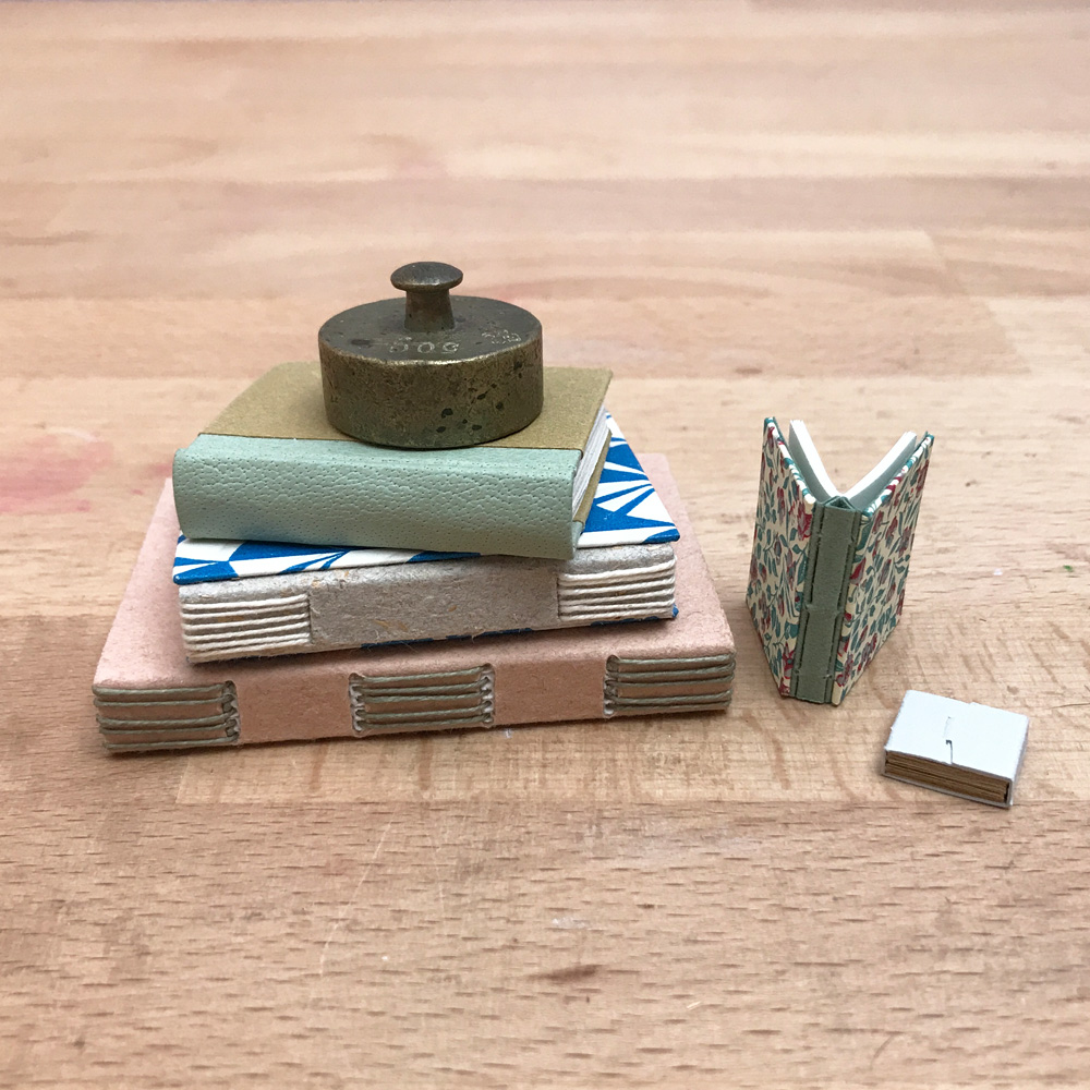 A variety of Miniature Bindings stacked on a wooden table.