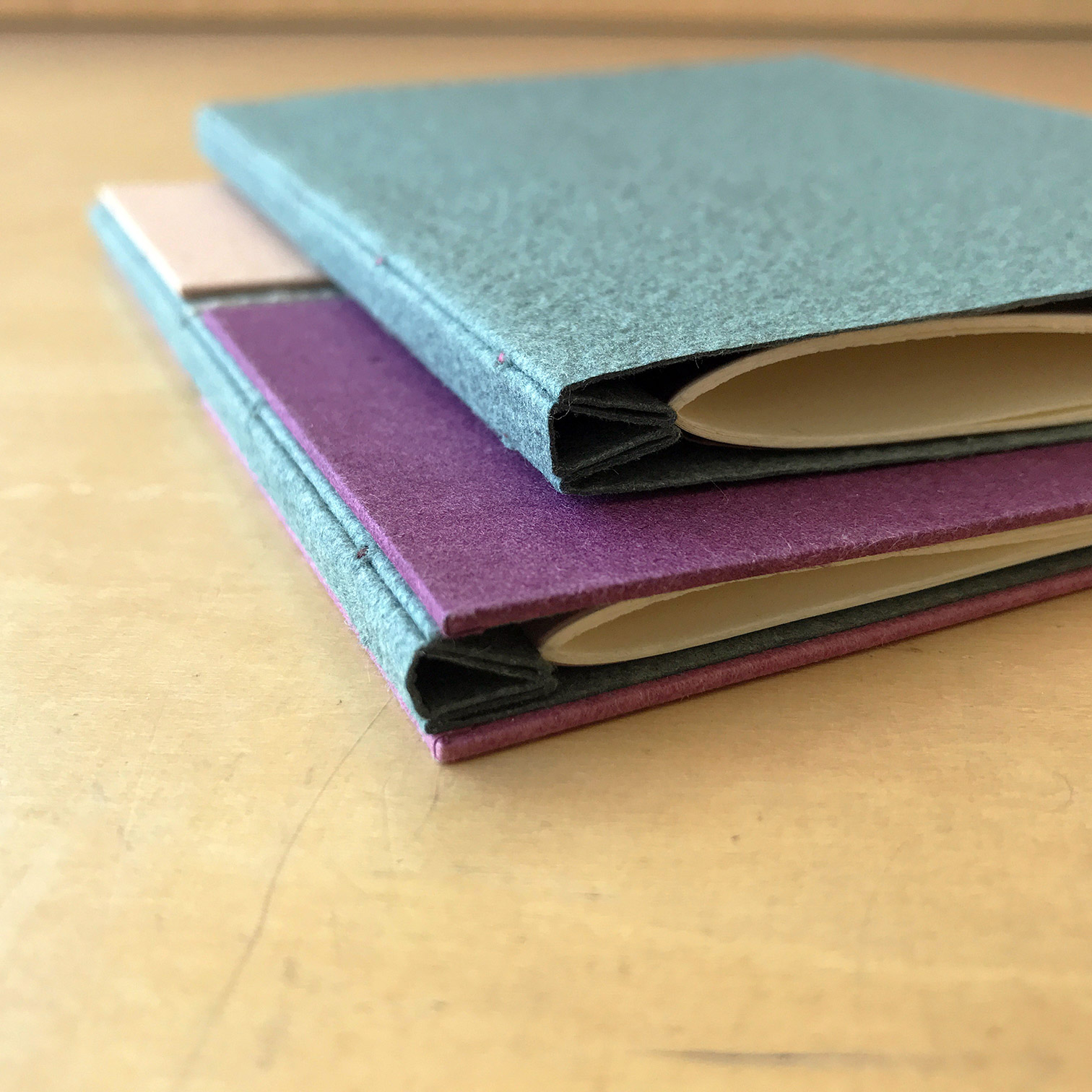 The spines of a variety of Single Signature Bindings on a wodden table.