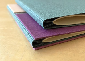 Two triangle stub bindings sitting on a wooden table.