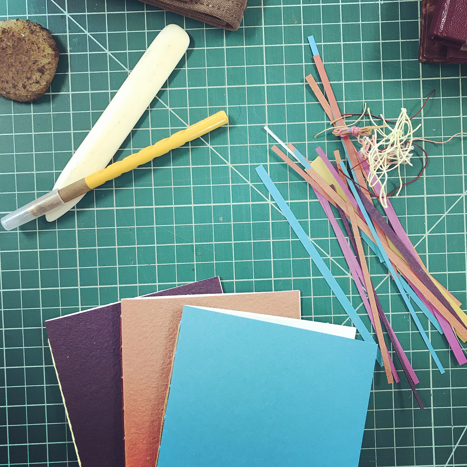 Single Signature Bindings and bookbinding tools sitting on a cutting matte.